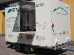 Mobiler Geschirrspüler auf Anhänger, mit geöffneter Klappe. Werbeflächen für regionale Partner.