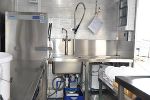 Mobiler Hygienebereich: Edelstahl-Arbeitsfläche mit Spüle, Wasserhahn und Abfallbehälter.